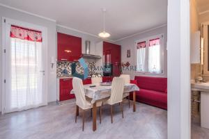 una cucina e un soggiorno con tavolo e divano rosso di Villa Laura a Lascari
