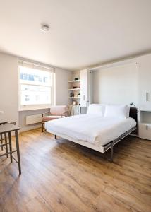 sypialnia z dużym białym łóżkiem i oknem w obiekcie Brand new studio flat in the heart of Notting Hill w Londynie