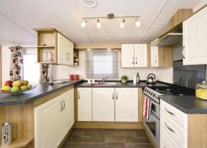 a kitchen with white cabinets and black counter tops at Lakeside Holiday Park in Burnham on Sea