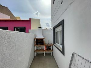 korytarzem białego budynku z oknem w obiekcie Happy House Barreiro w mieście Barreiro