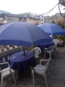 dos sombrillas azules sobre mesas y sillas bajo la lluvia en Hotel tanta Wasi, en Quito