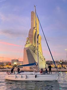 里斯本的住宿－Veleiro Oceanico de 12 m，雕像前水面上的帆船