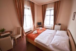 a bedroom with a bed and a desk and two windows at Hotel Paradies in Teplice
