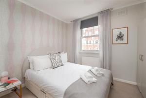 - une chambre avec un lit blanc et des serviettes dans l'établissement Fantastic two bedroom apartment in vibrant Kings Cross by UnderTheDoormat, à Londres