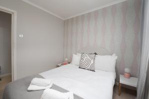 - une chambre blanche dotée d'un lit avec des draps et des oreillers blancs dans l'établissement Fantastic two bedroom apartment in vibrant Kings Cross by UnderTheDoormat, à Londres