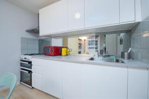 - une cuisine blanche avec évier et cuisinière dans l'établissement Fantastic two bedroom apartment in vibrant Kings Cross by UnderTheDoormat, à Londres