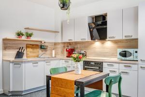 a kitchen with white cabinets and a table with flowers on it at Pressehaus Apartment Steinweg in Mühlhausen +9 photos