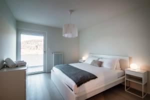 Dormitorio blanco con cama y ventana grande en La Palma 2 by Quokka 360 - spacious flat with lake view, en Montagnola