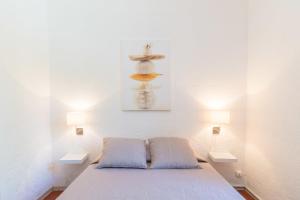 una camera da letto con un letto con due cuscini e due luci di Le Mas, maison au charme provençale idéalement située entre mer et vignes a Hyères