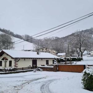 una casa con nieve en el suelo delante de ella en Casa rural altza erreka en Errazu
