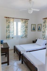 sypialnia z 2 łóżkami, stołem i oknem w obiekcie AEGEA MILOS w mieście Adamas
