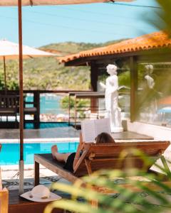 a woman laying on a bench with a laptop at Le Village Boutique Hotel in Búzios +85 photos