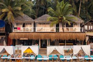 a resort with chairs and a building with palm trees at The Shore beach resort Palolem in Canacona