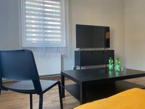 a living room with a black table and a tv at Centrum No. 1 in Polanica-Zdrój