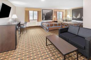 a hotel room with a couch and a bed and a television at Super 8 by Wyndham League City Kemah Area in League City