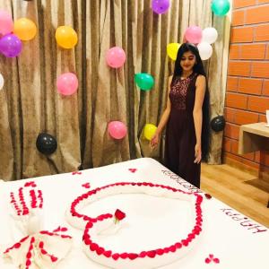 Una donna in piedi davanti a un tavolo con una torta di Serene Crest Resort a Mananthavady