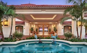 a swimming pool in front of a house with palm trees at Park Hyatt Aviara in Carlsbad
