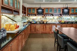 a large kitchen with wooden cabinets and a bar at Hyatt Place Denver Airport in Aurora