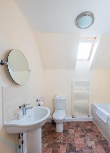 ein Badezimmer mit einem Waschbecken, einem WC und einem Spiegel in der Unterkunft The Granary with Hot Tub in Forgandenny