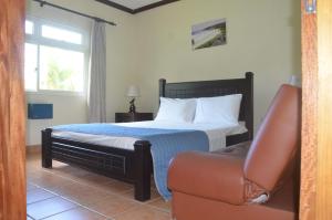 een slaapkamer met een bed, een bank en een raam bij Butterfly Villas in Grand'Anse Praslin