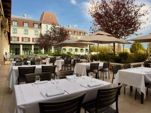 un restaurant avec des tables blanches, des chaises et des parasols dans l'établissement Radisson Blu Hotel Paris, Marne-la-Vallée, à Magny-le-Hongre