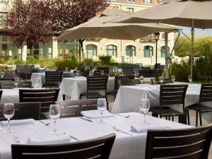 a restaurant with white tables and chairs and umbrellas at Radisson Blu Hotel Paris, Marne-la-Vall&eacute;e in Magny-le-Hongre