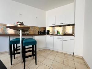 a kitchen with white cabinets and a table and stool at Gemütliches Apartment mit Blick zur Frauenkirche in Dresden