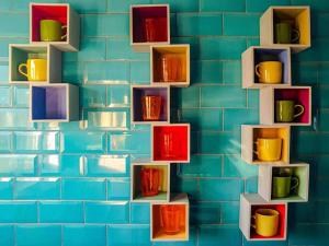 a blue tiled wall with colorful cups on shelves at The Beach Hut in Scratby