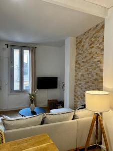 een woonkamer met een bank en een bakstenen muur bij Chez Lise in Montpellier