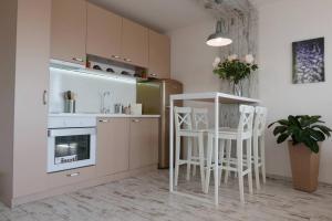 a kitchen with white chairs and a table and a refrigerator at Charmful new flat with Hill view in Plovdiv