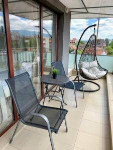 a balcony with two chairs and a table and a swing at Charmful new flat with Hill view in Plovdiv