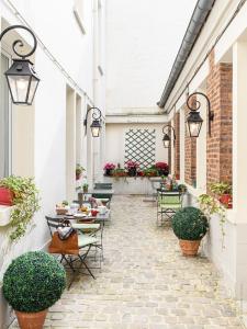 un patio al aire libre con mesas, sillas y luces en A l'Hôtel Des Roys, en Versalles