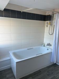 a white bath tub in a white tiled bathroom at Hotel Penwig in New Quay