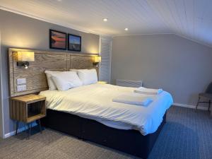 um quarto de hotel com uma cama grande com lençóis brancos em Hotel Penwig em New Quay