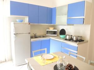 a small kitchen with blue cabinets and a table at Beautiful Two-Bedroom Villa in Bibione - Beahost in Bibione