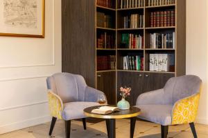 duas cadeiras e uma mesa em frente a uma estante de livros em Best Western Royal Hotel Caen em Caen