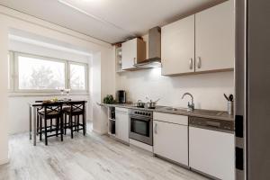 a kitchen with white cabinets and a table at Ferienwohnung Arkadia Zentrale in Norderstedt