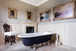 ein großes Bad mit einer großen Badewanne und Gemälden in der Unterkunft The Casterton Grange Estate in Kirkby Lonsdale