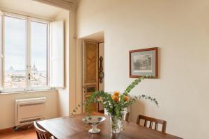 a dining room with a table with a vase of flowers on it at iFlat Spanish Steps at your Feet in Rome