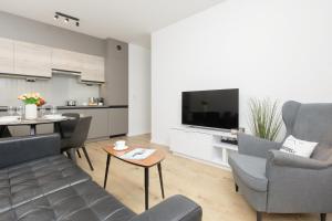 uma sala de estar com um sofá e cadeiras e uma televisão em Two-Bedroom Elegant Apartment with Parking Warsaw Praga by Renters em Varsóvia