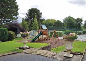 a park with a playground with a swing at Woodlands Hall in Ruthin