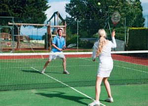 a man and a woman playing tennis on a tennis court at Woodlands Hall in Ruthin