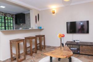 a living room with three wooden stools and a tv at PachobyDaisy in Awasi