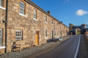 un edificio de piedra con un banco junto a una calle en Castle Cottage, a self-catering cottage full of character., en Amhuinnsuidhe