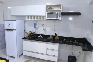 eine weiße Küche mit einer Spüle und einem Kühlschrank in der Unterkunft Flat 106 próximo a orla in Aracaju