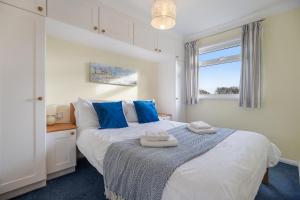 a bedroom with a bed with blue pillows and a window at 17 Norton Park in Dartmouth