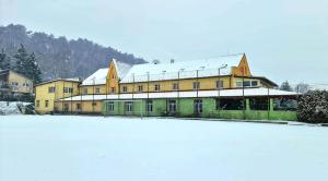 a large building with snow on top of a snow covered field at Penzion Olympia in Banská Bystrica