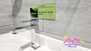 a bathroom sink with a sign on the wall at Desaru Dhancell Executive Homestay Netflix,8Pax,Wifi in Desaru +26 photos
