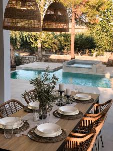 a wooden table with chairs and a table with plates and glasses at Luxury Villa Anemone with private pool in Pastida