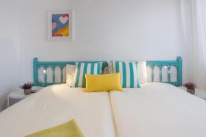 Bett mit blauem Kopfteil und gelbem Kissen in der Unterkunft MalagaSuite Pier Fuengirola in Fuengirola